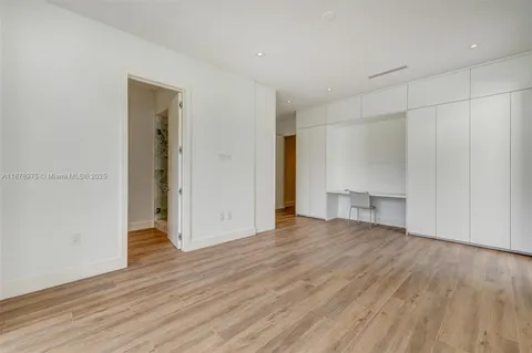 a view of an empty room with wooden floor and closet