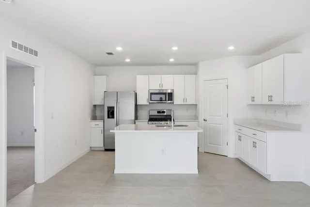 a kitchen with kitchen island a sink a stove a refrigerator and white cabinets