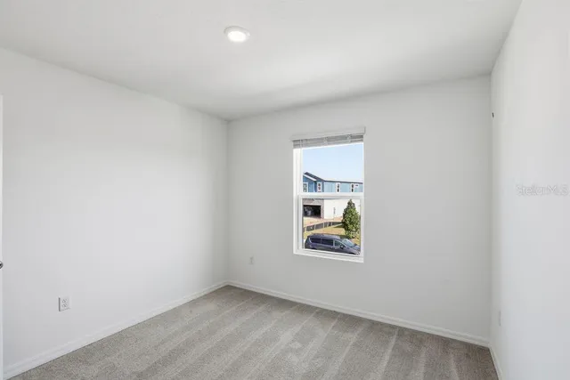 a view of an empty room with closet and a window
