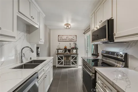 a kitchen with stainless steel appliances granite countertop a stove top oven a sink a refrigerator and cabinets