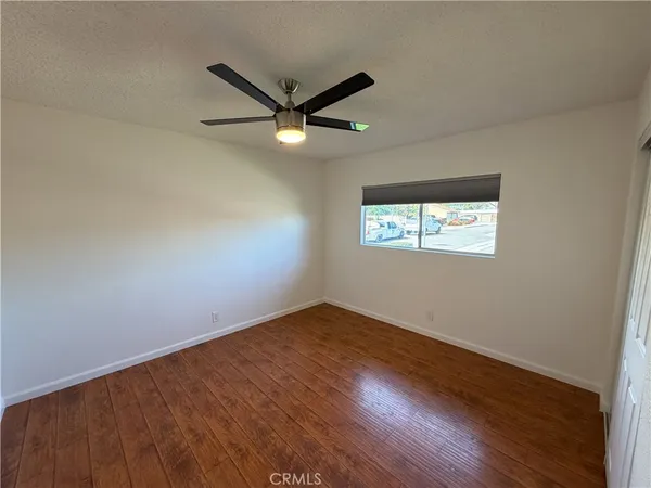 an empty room with wooden floor ceiling fan and windows