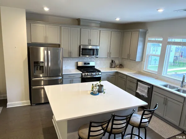 a kitchen with a table chairs microwave and refrigerator