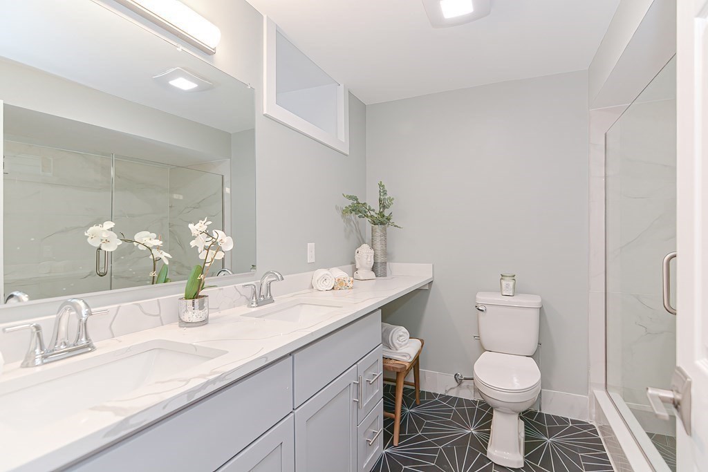 287 Cherry Street, Unit 1 Newton, MA 02465 - Photo 22 of 30 a bathroom with a granite countertop toilet sink and a mirror