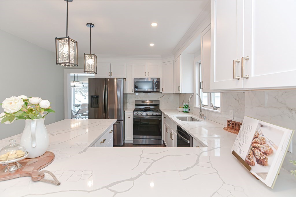 287 Cherry Street, Unit 1 Newton, MA 02465 - Photo 8 of 30 a kitchen with stainless steel appliances granite countertop a refrigerator a sink dishwasher a stove a dining table and chairs with wooden floor