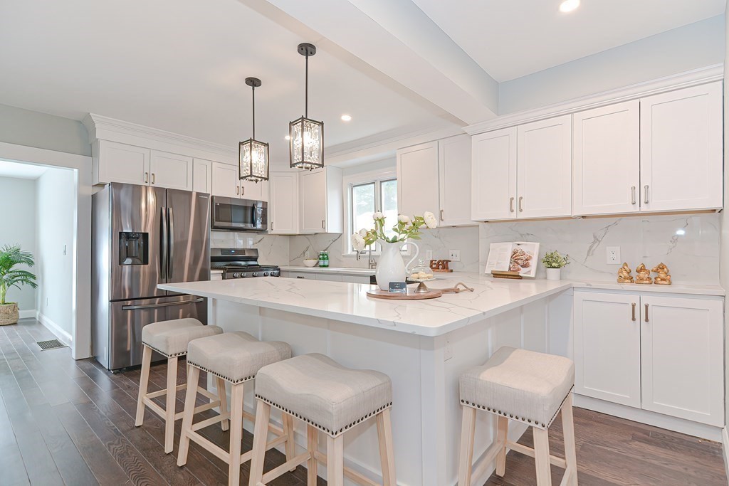 287 Cherry Street, Unit 1 Newton, MA 02465 - Photo 9 of 30 a kitchen with stainless steel appliances a sink a stove a refrigerator and white cabinets with wooden floor