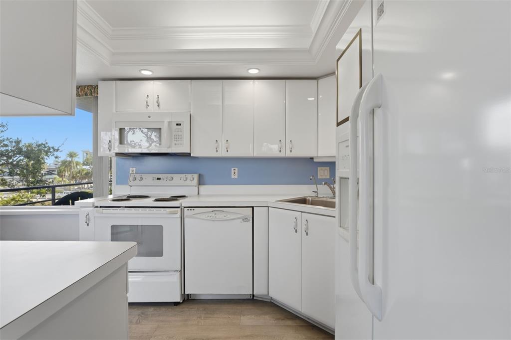 6415 Midnight Pass Road, Unit 310 Sarasota, FL 34242 - Photo 18 of 62 a kitchen with white cabinets and white appliances