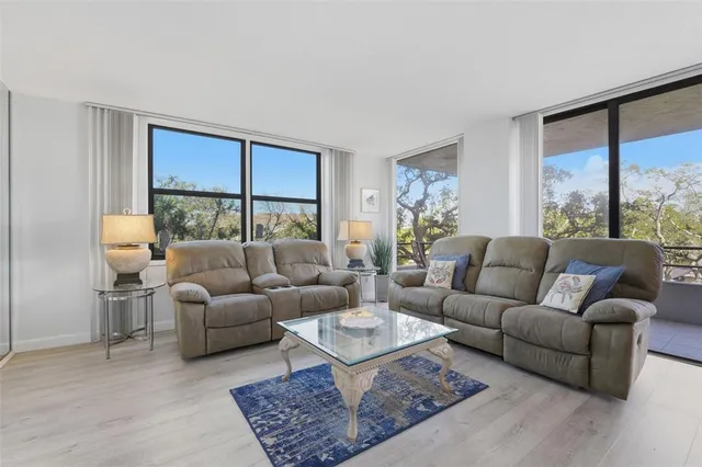 a living room with furniture a rug a lamp and a large window