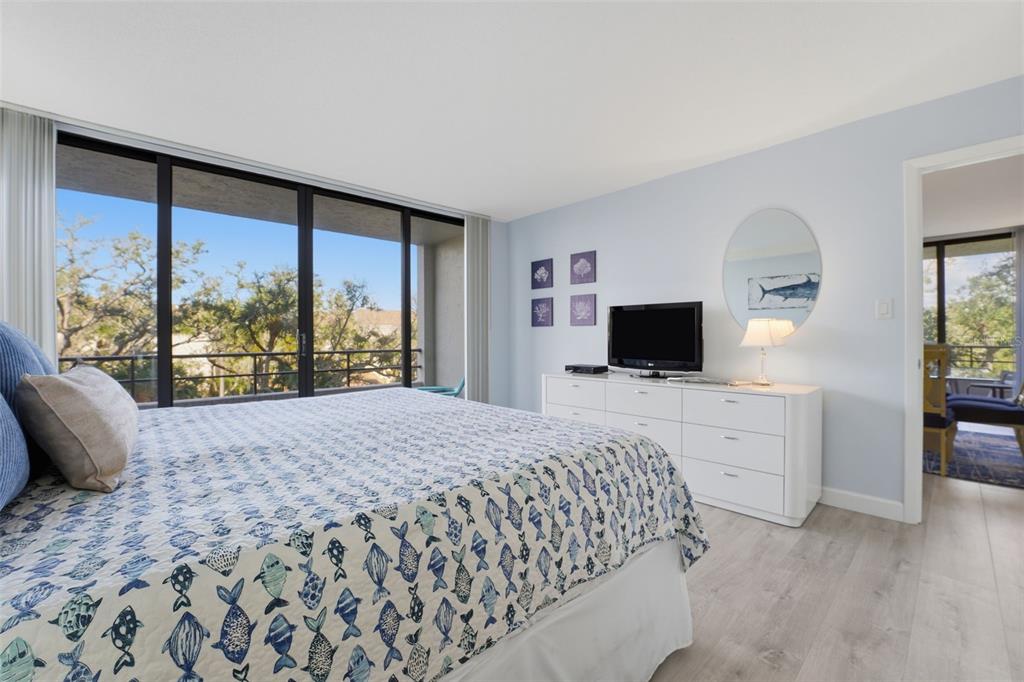 6415 Midnight Pass Road, Unit 310 Sarasota, FL 34242 - Photo 10 of 62 a bedroom with a large bed and a flat tv screen on dresser