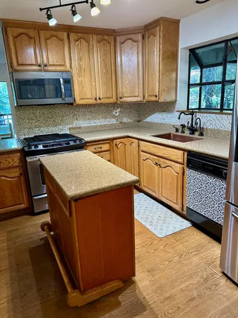 a kitchen with kitchen island granite countertop wooden cabinets a sink and a stove
