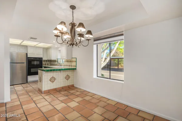 a kitchen with stainless steel appliances granite countertop a sink a stove a refrigerator a window and a dining table