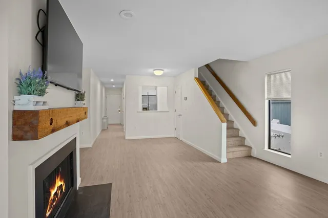 a view of an empty room with wooden floor and a fireplace