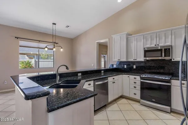 a kitchen with kitchen island granite countertop a sink stove and cabinets