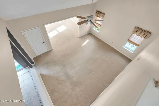 an empty room with windows and chandelier fan