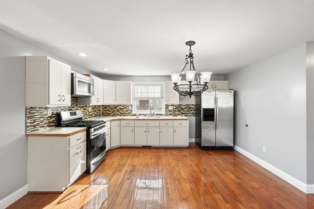 70 West High Street, Unit 2 Avon, MA 02322 - Photo 3 of 22 a kitchen with stainless steel appliances granite countertop a sink cabinets and wooden floor