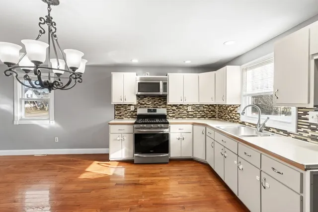 a kitchen with stainless steel appliances granite countertop a sink a stove a refrigerator cabinets and a window