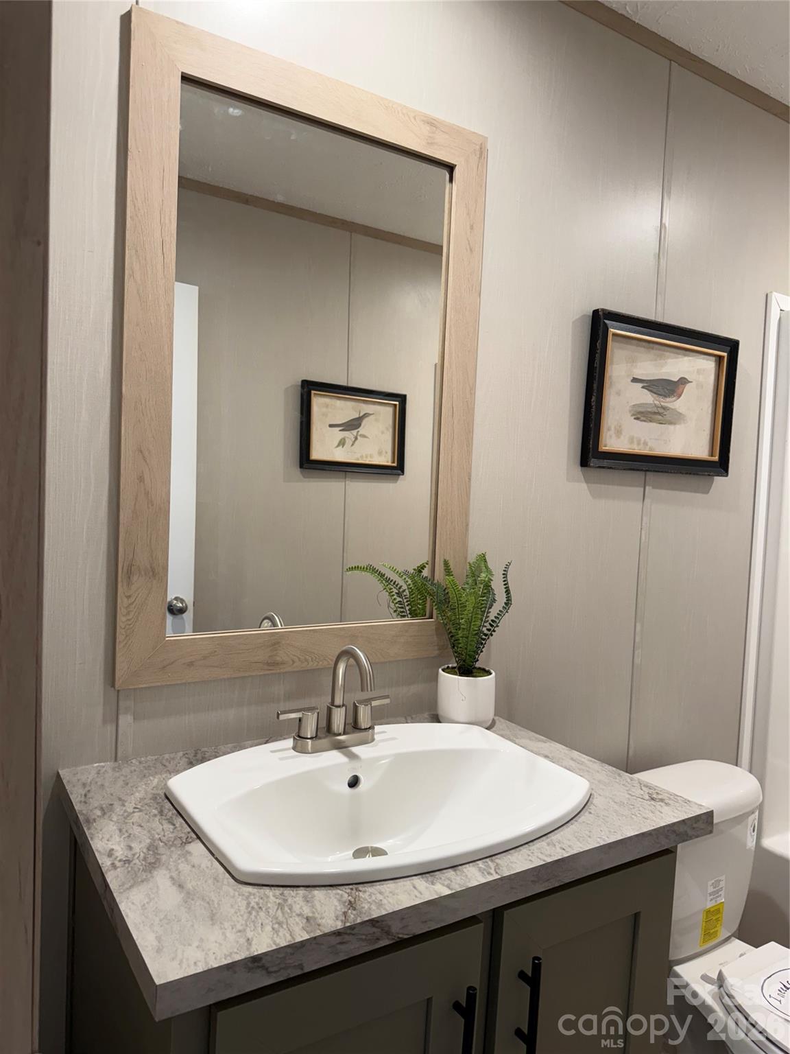 516 Lake Mullis Road Harmony, NC 28634 - Photo 9 of 28 a bathroom with a granite countertop sink a toilet and mirror