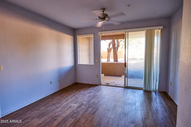 a view of an empty room with a window and wooden floor