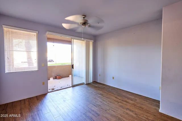 a view of empty room with wooden floor and fan