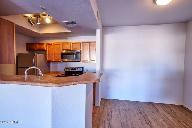 a kitchen with stainless steel appliances granite countertop a sink a stove top oven a chimney and a counter top space