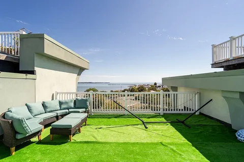 a view of a deck with couches chairs and wooden fence