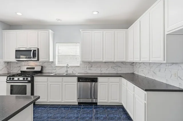 a kitchen with granite countertop white cabinets and stainless steel appliances