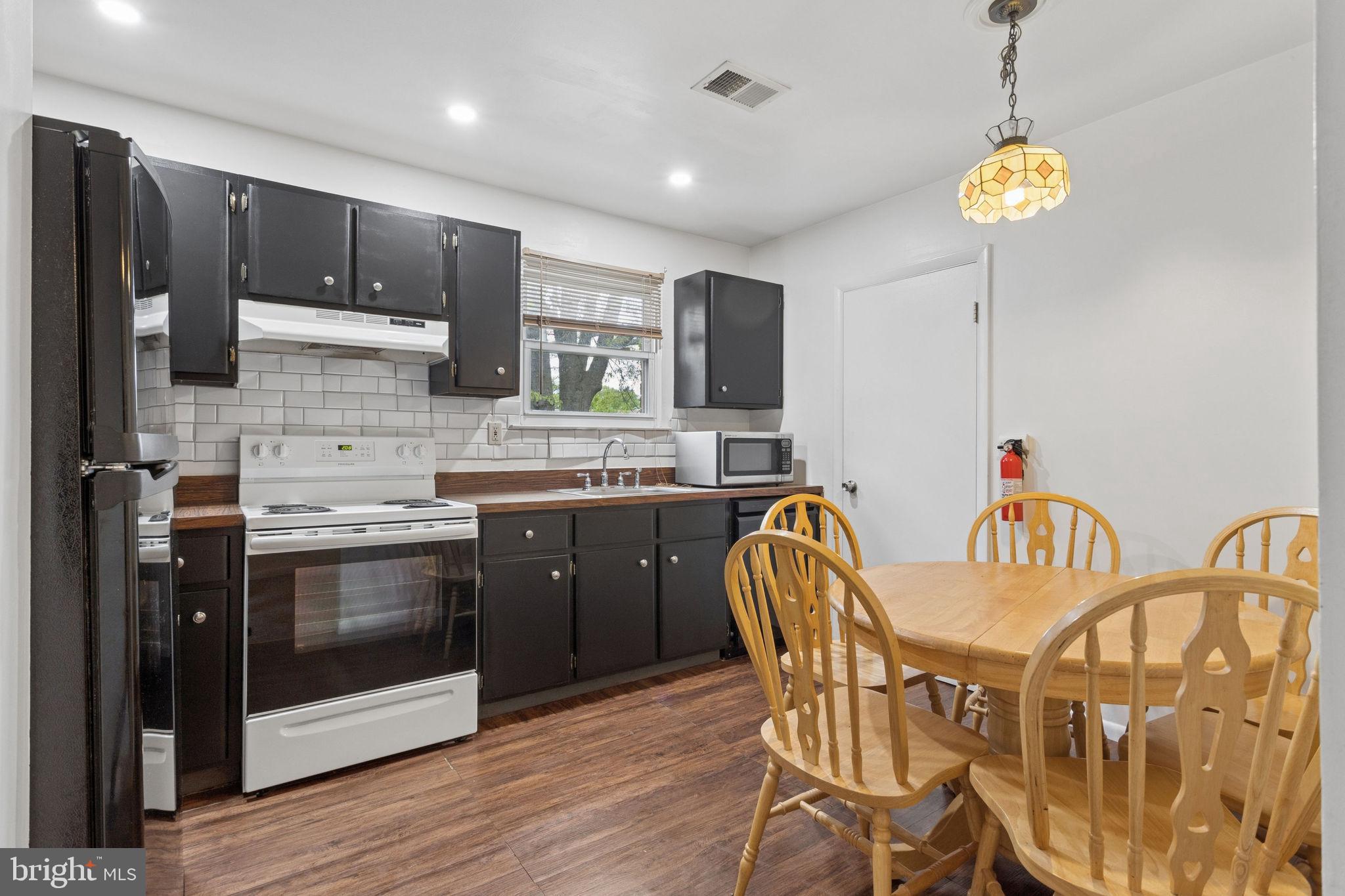 1475 Mt Holly Road, Unit R3 Edgewater Park, NJ 08010 - Photo 9 of 19 a kitchen with stainless steel appliances granite countertop a kitchen island hardwood floor sink stove dining table and chairs