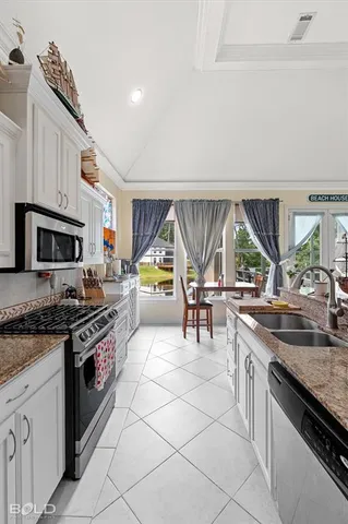 a kitchen with stainless steel appliances granite countertop a stove a sink and a microwave