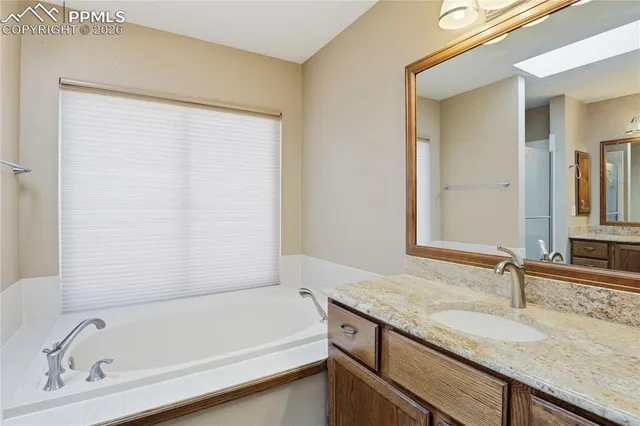 a bathroom with a granite countertop sink and a bathtub