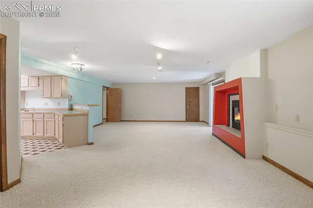 a view of an empty room with kitchen and window