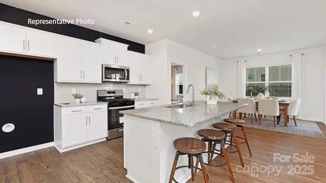 a kitchen with stainless steel appliances granite countertop a stove a sink dishwasher and a refrigerator with wooden floor