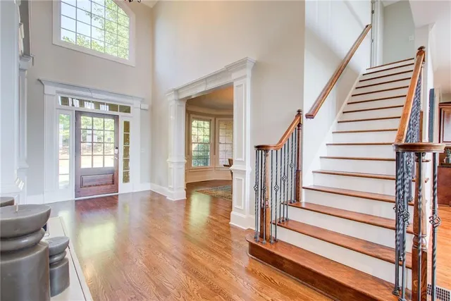 a view of an empty room with wooden floor and a ceiling fan