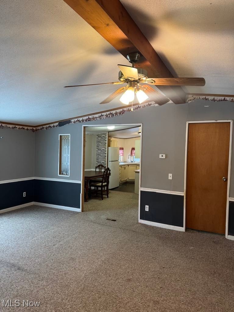 2385 Chase Road Southeast Carrollton, OH 44615 - Photo 8 of 16 Carpeted spare room featuring ceiling fan, lofted ceiling with beams, and a textured ceiling