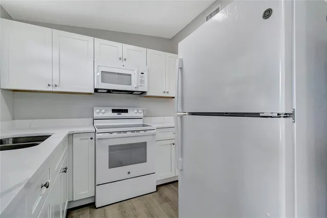a kitchen with white cabinets and white appliances