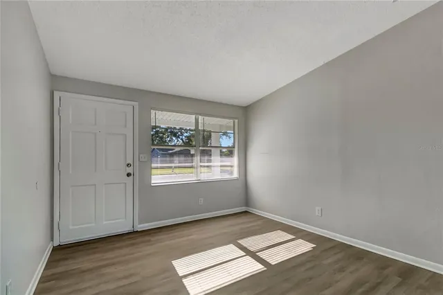 an empty room with wooden floor and window