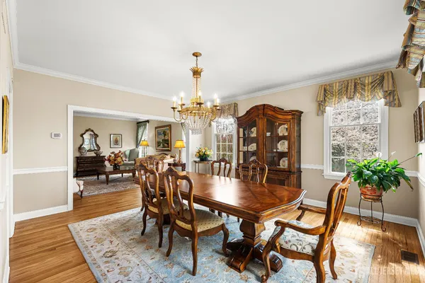 a kitchen with stainless steel appliances granite countertop a kitchen island a stove a refrigerator a sink a dining table and chairs with wooden floor