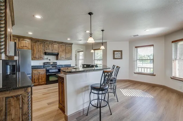 a kitchen with stainless steel appliances granite countertop wooden floor dining table and chairs