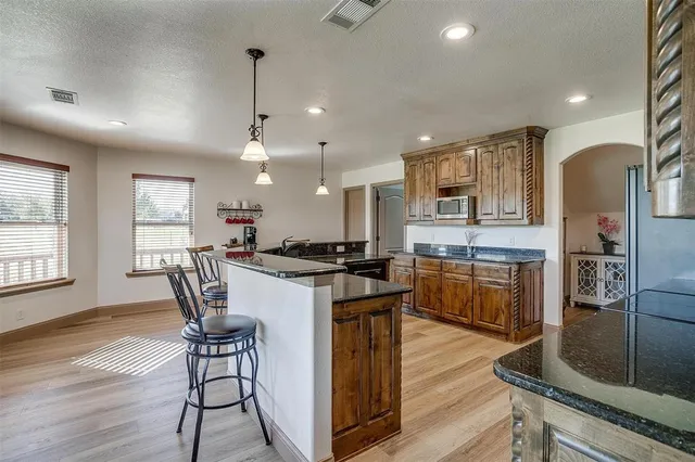 a kitchen with stainless steel appliances granite countertop a stove a refrigerator a oven a sink with a dining table and chairs