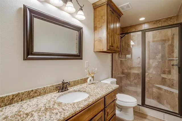 a bathroom with a granite countertop sink toilet and shower