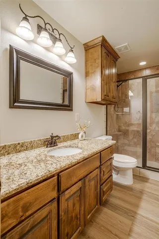 a bathroom with a granite countertop sink a toilet and a mirror