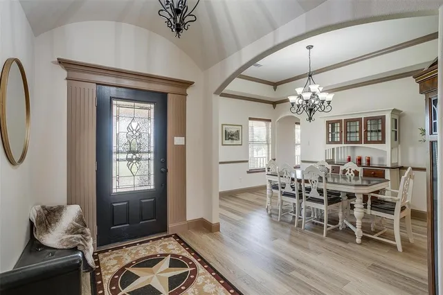 a dining room with wooden floor a chandelier a glass table and chairs