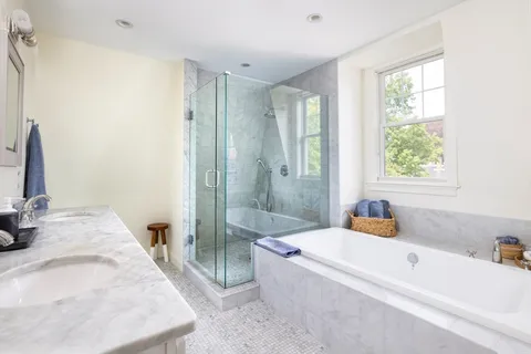 a bathroom with a tub a sink and a large mirror