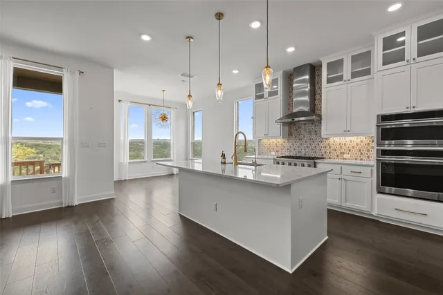 a kitchen with stainless steel appliances kitchen island wooden floors wooden cabinets and white appliances