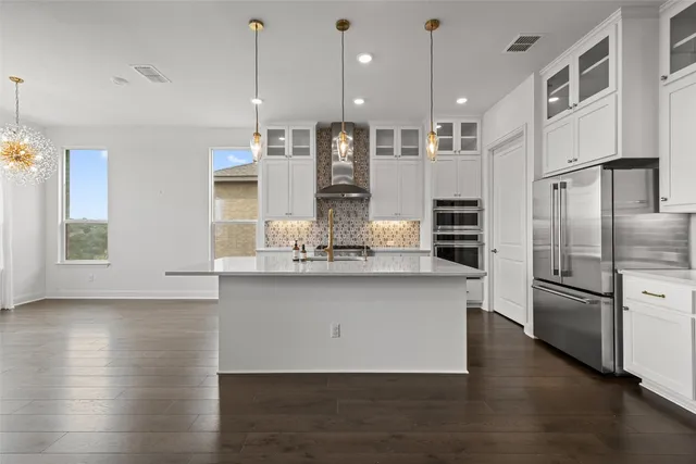 a kitchen with stainless steel appliances granite countertop wooden floors and white cabinets