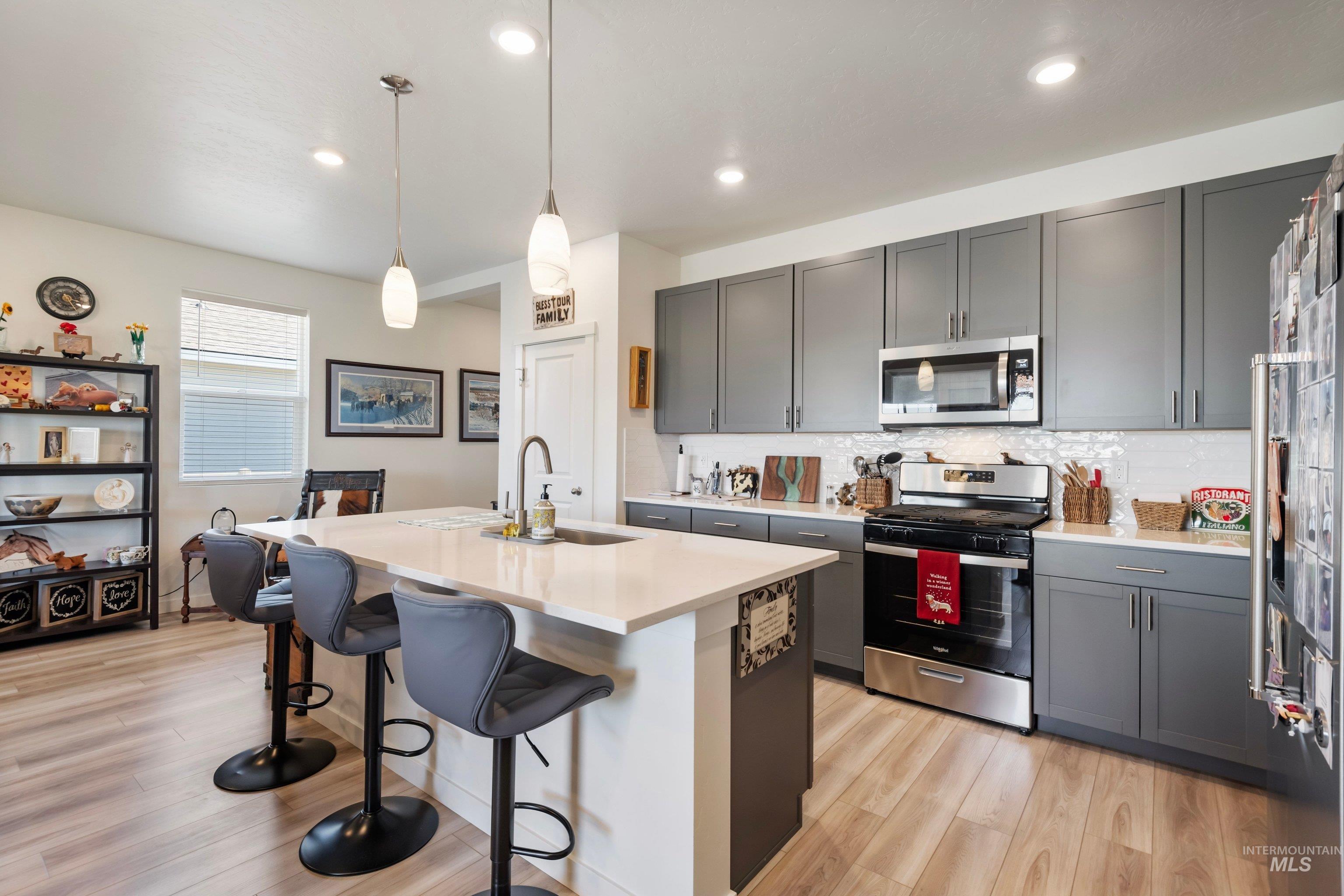 4232 South Graycliff Way Meridian, ID 83642 - Photo 13 of 34 Open-concept kitchen featuring an island with seating, pendant lighting, stainless steel appliances, and gray cabinetry