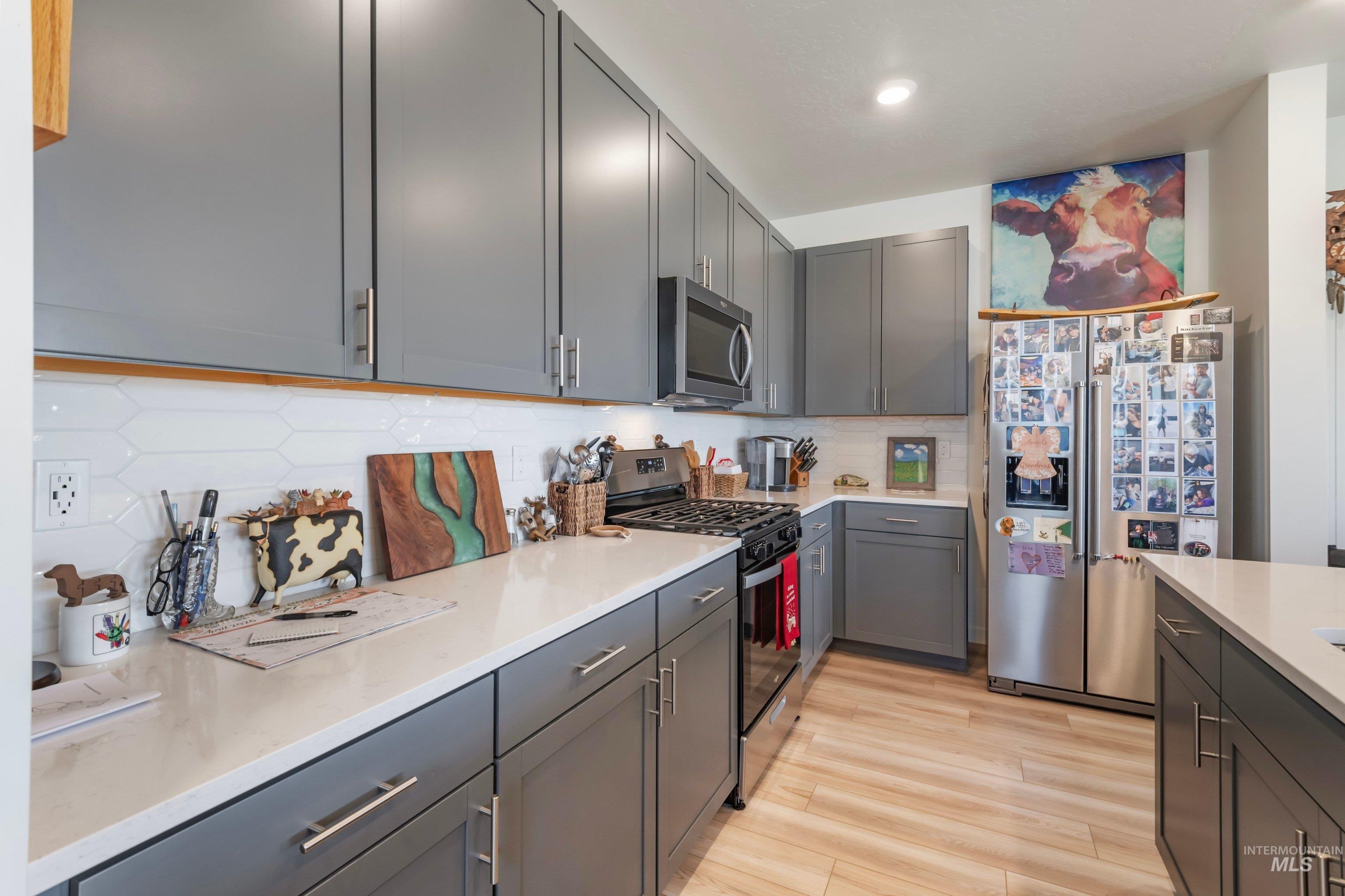 4232 South Graycliff Way Meridian, ID 83642 - Photo 14 of 34 Modern kitchen featuring gray cabinetry with brushed nickel hardware, light-toned countertops, and a white geometric tile backsplash