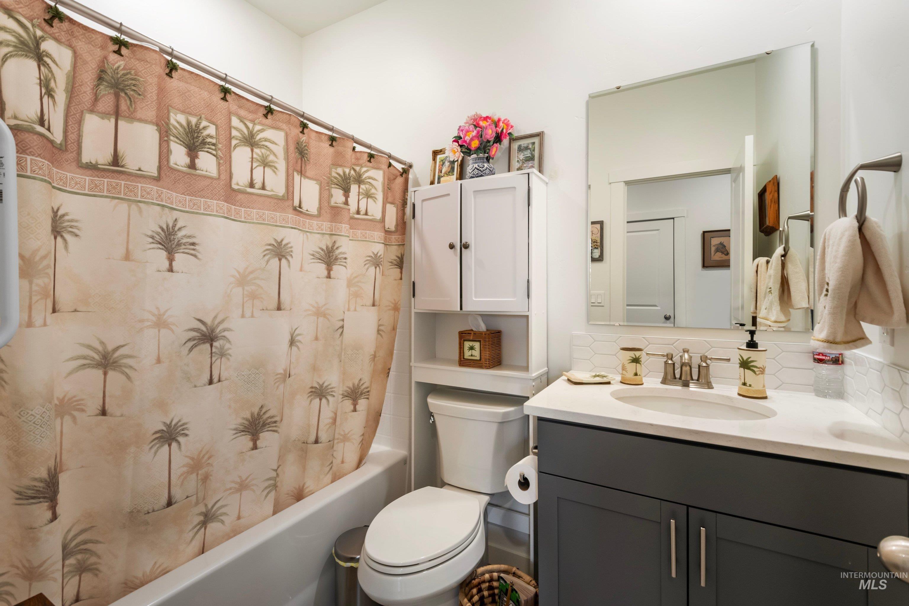 4232 South Graycliff Way Meridian, ID 83642 - Photo 21 of 34 Bathroom featuring a white tub, built-in vanity with a white countertop and undermount sink, a large mirror, and a wall-mounted storage cabinet
