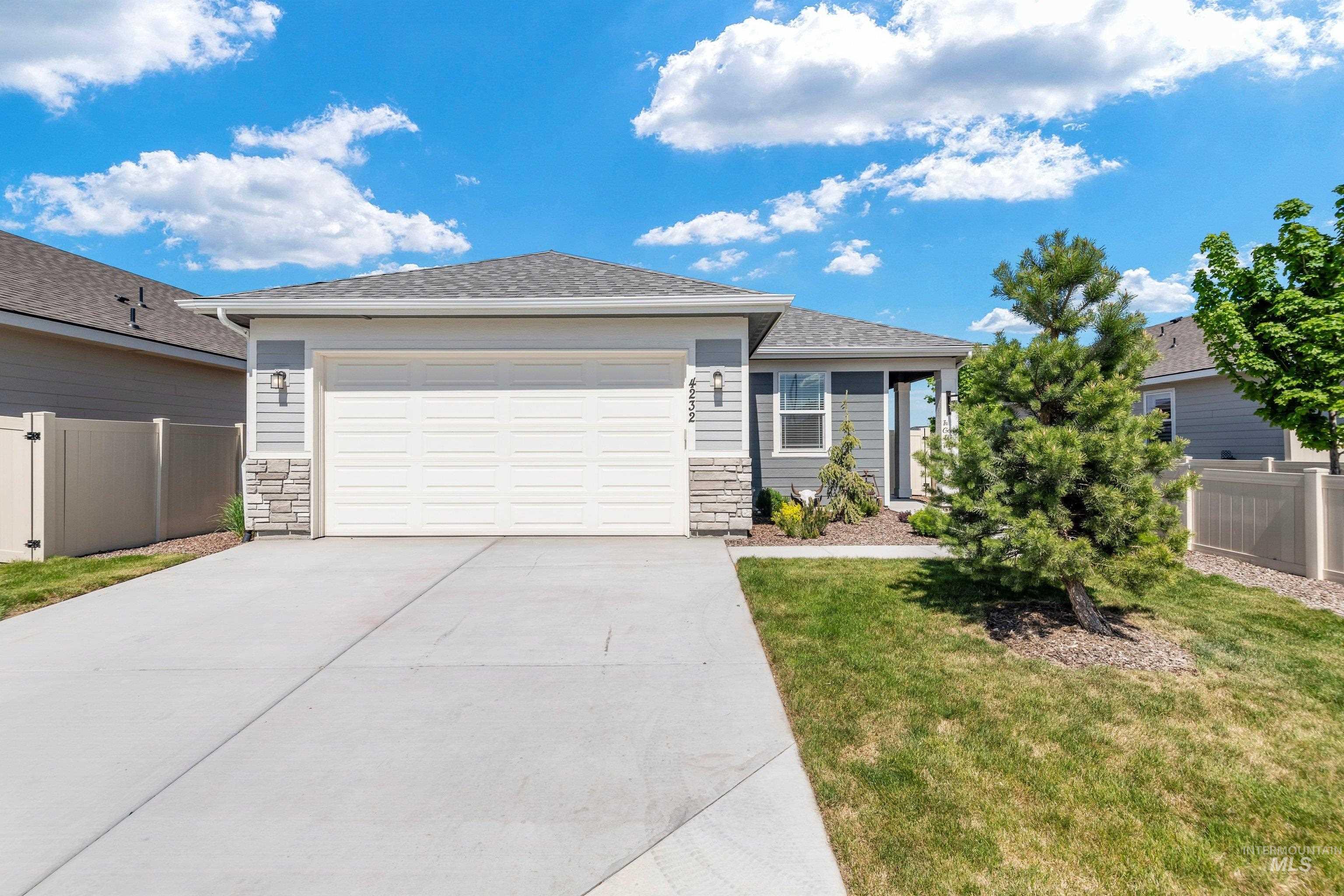 4232 South Graycliff Way Meridian, ID 83642 - Photo 4 of 34 Modern ranch-style residence featuring grey horizontal siding, stone veneer accents, and a white garage door