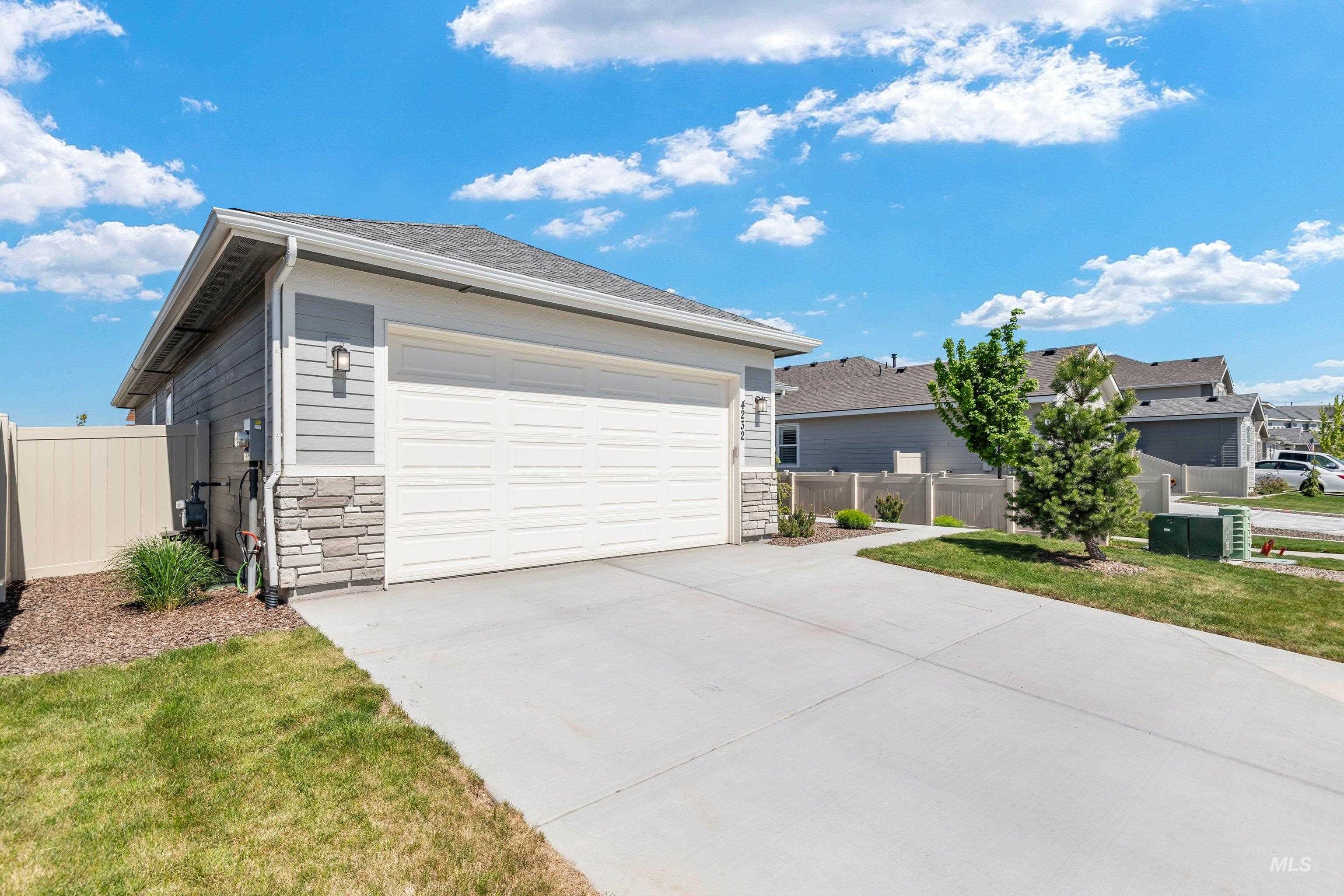 4232 South Graycliff Way Meridian, ID 83642 - Photo 6 of 34 Attached garage with a white panel door, gray horizontal siding, and a stacked stone accent