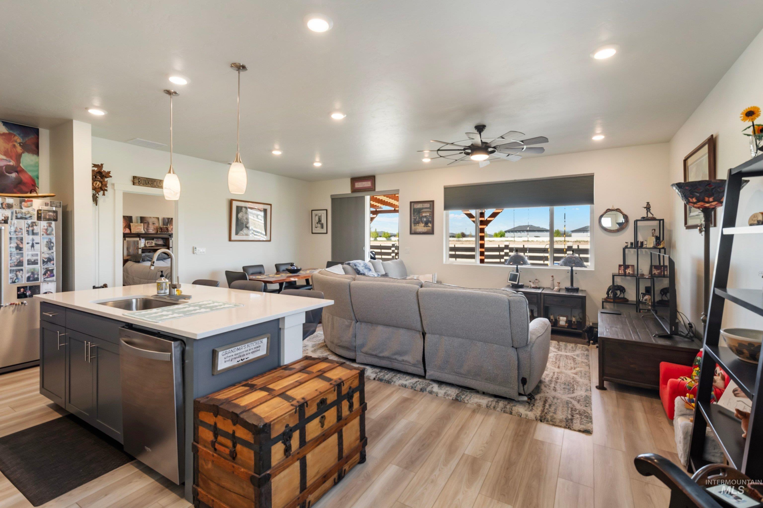 4232 South Graycliff Way Meridian, ID 83642 - Photo 9 of 34 Open-concept living space featuring a kitchen island with sink, stainless steel appliances, recessed lighting, and wood-finish flooring