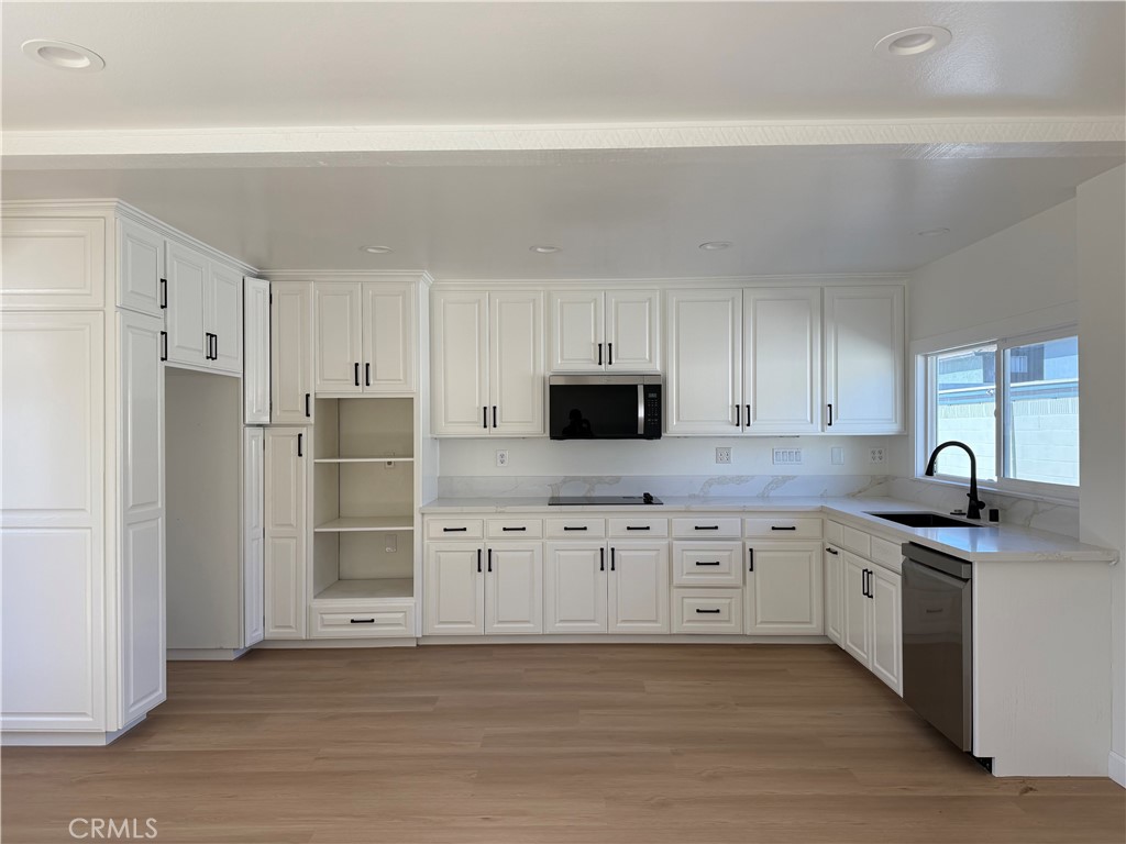 6441 St Paul Circle, Unit A Huntington Beach, CA 92647 - Photo 4 of 13 a kitchen with granite countertop a refrigerator sink and white cabinets